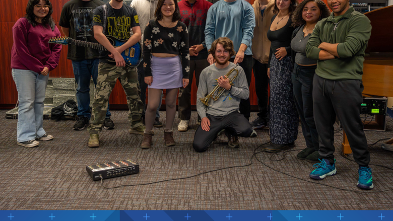 a group of students smile in a room full of instruments